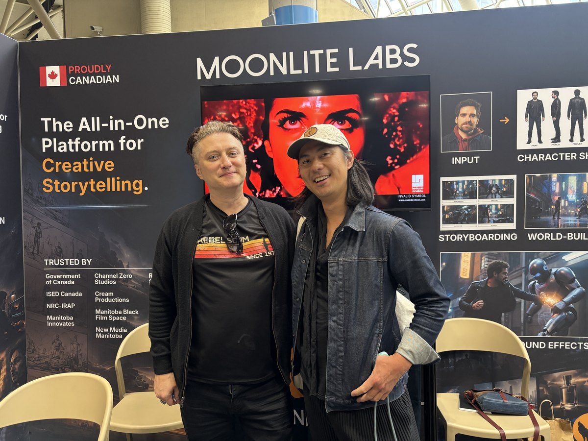 Two visitors posing in front of the Moonlite Labs booth wall